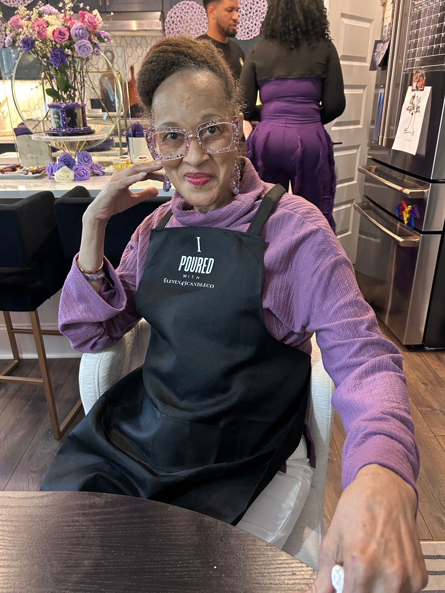 The birthday honoree in sparkly pink glasses and an I Poured With Eleven45 apron posing at the candle-making table