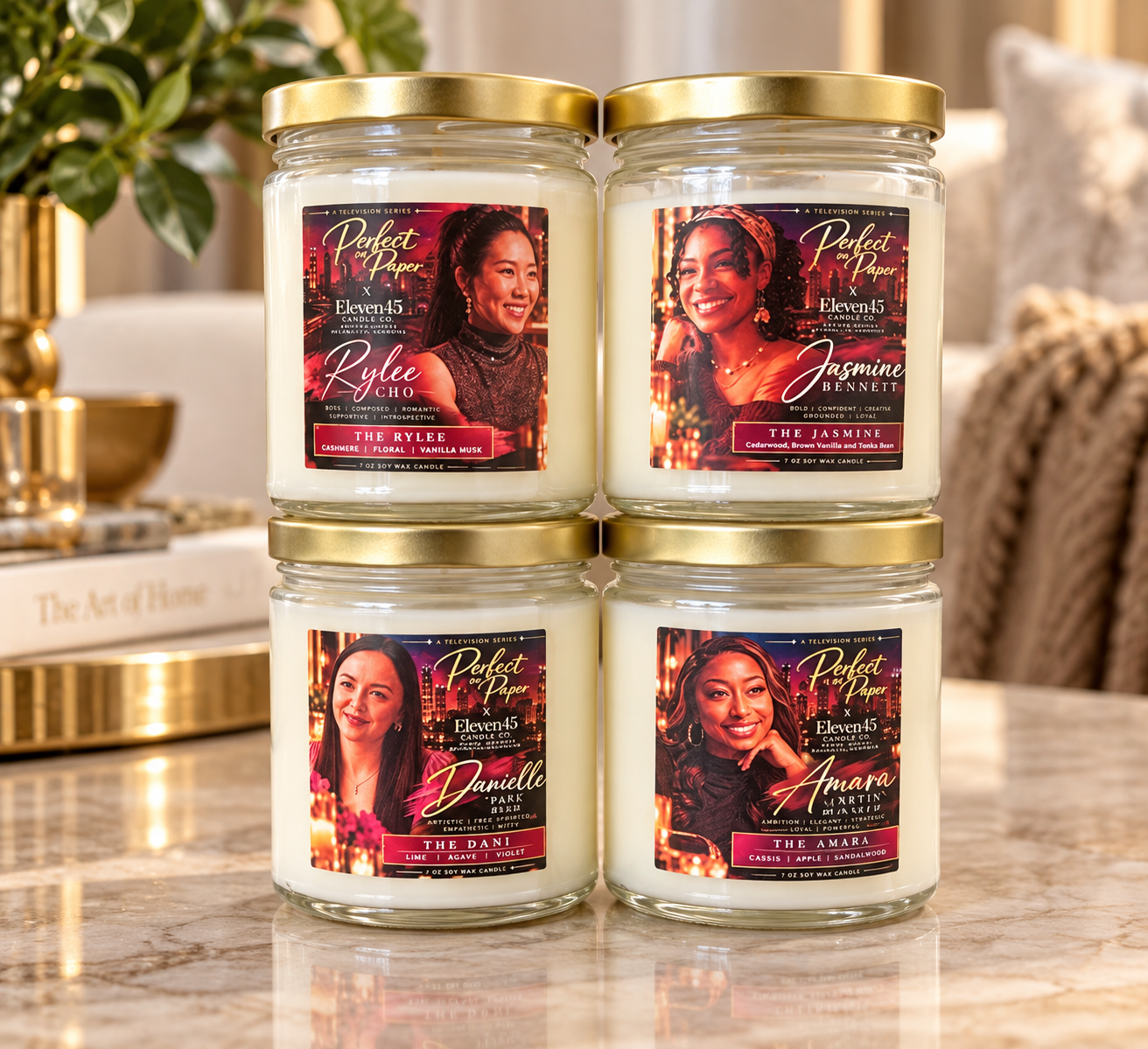 Four gold-lid candles with character labels from the television series Perfect on Paper, made with Eleven45 Candle Co.